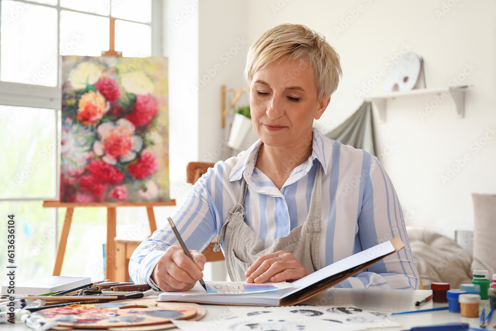 Mature female artist drawing sketch in  workshop