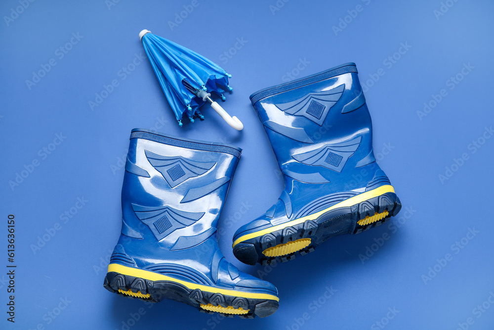 Gumboots and mini umbrella on dark blue background