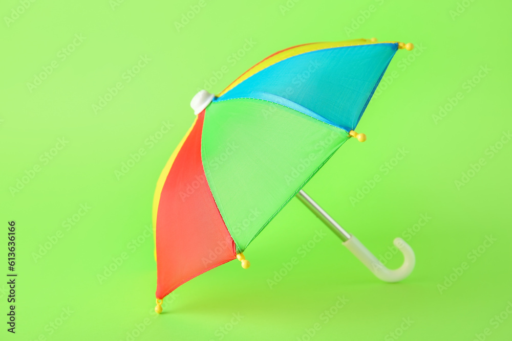 Mini colorful umbrella on green background