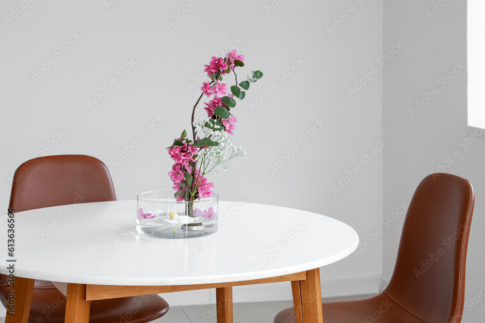 Beautiful ikebana on dining table in light room