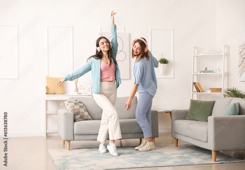 Female friends in headphones dancing at home