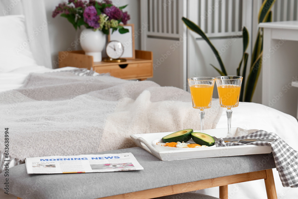 Tasty breakfast with newspaper on bench in bedroom