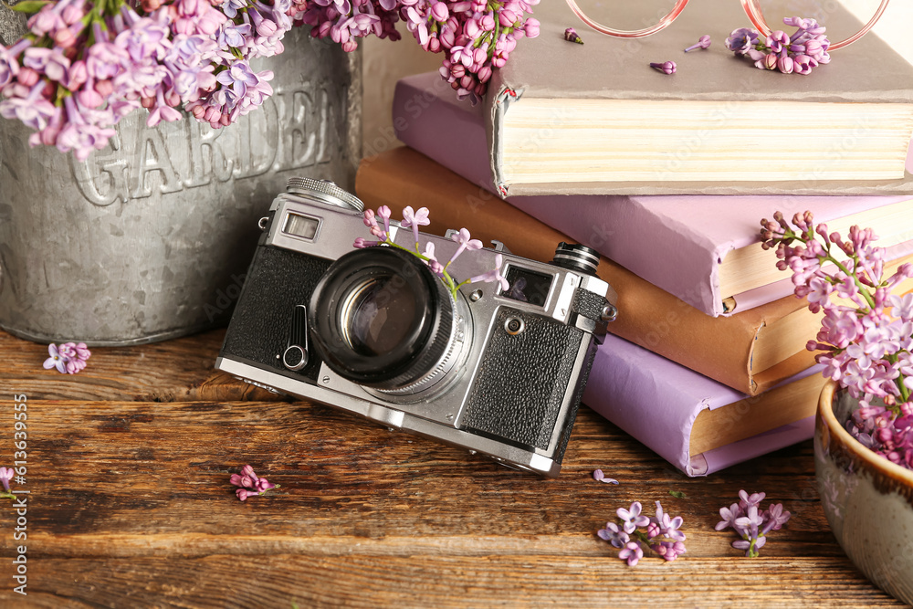 Composition with camera, notebooks and lilac twigs on wooden table