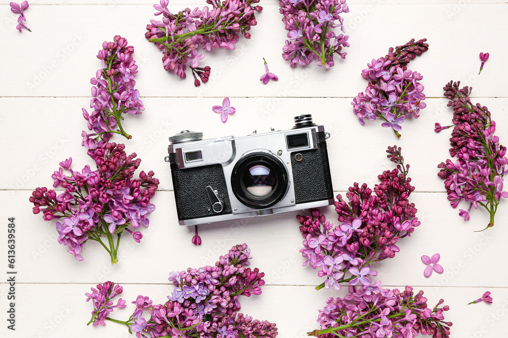 Lilac twigs with camera on white wooden table