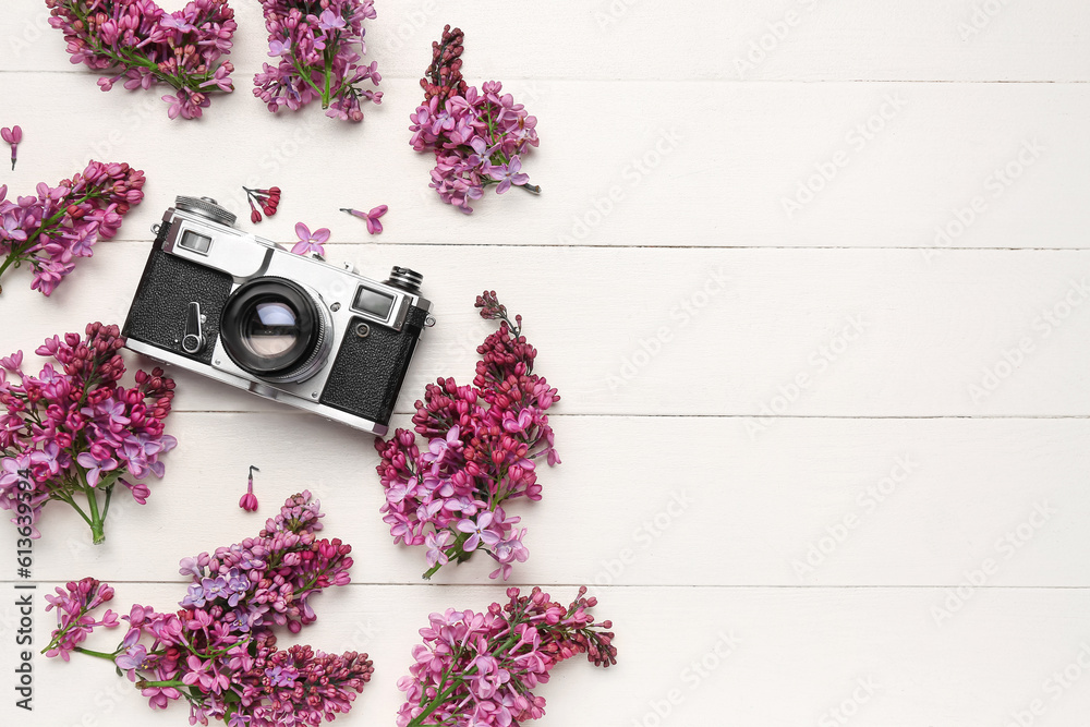 Lilac twigs with camera on white wooden table