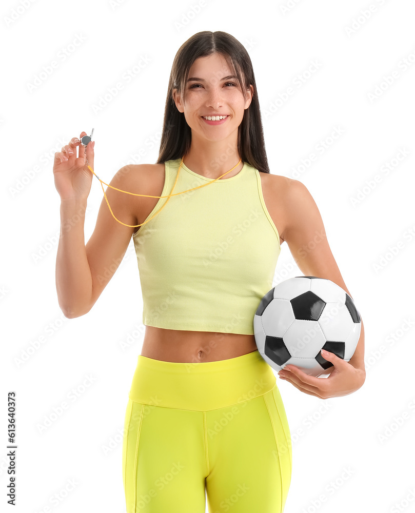 Sporty female coach with soccer ball and whistle on white background