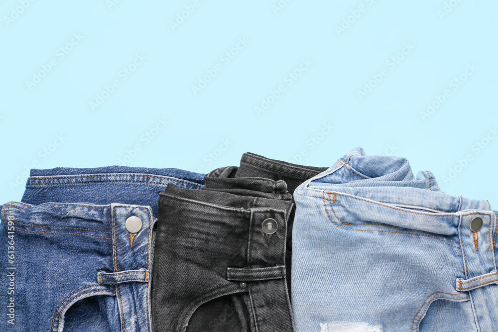 Different folded jeans on blue background