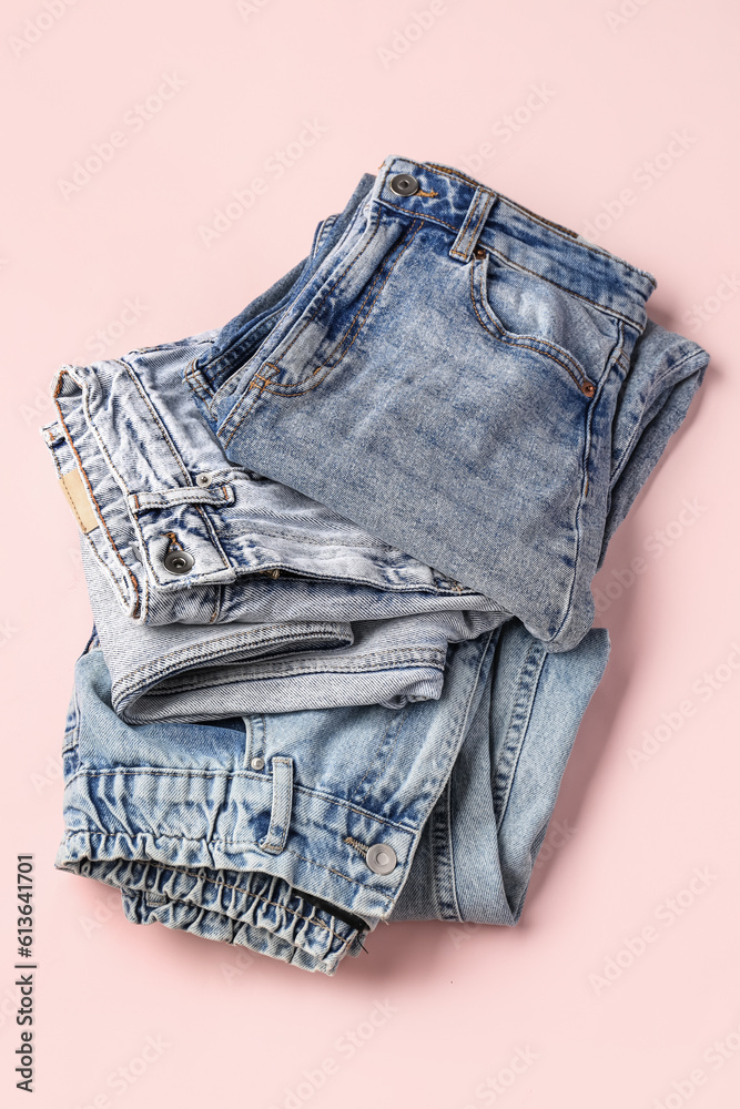 Different folded jeans on pink background