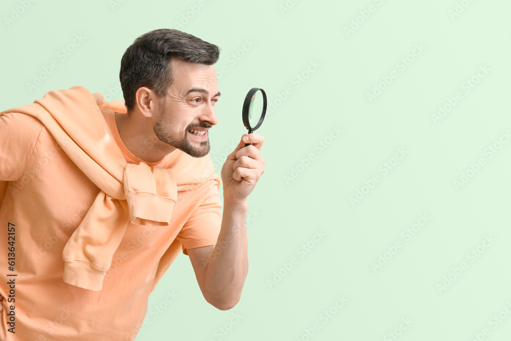 Handsome man with magnifier on green background