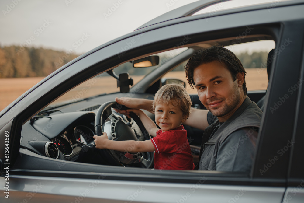 Father with his two-year-old son driving car in a field