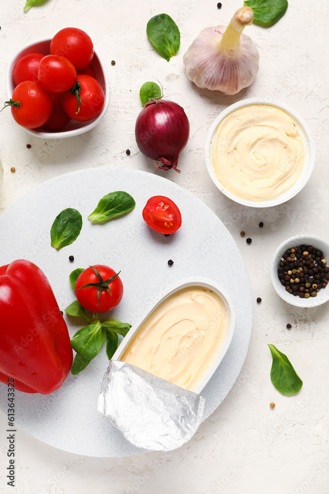 Plastic containers with tasty cream cheese and fresh vegetables on light background