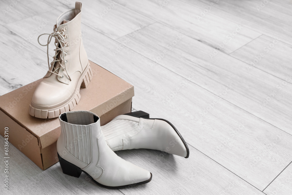 Cardboard box with female boots on light wooden background