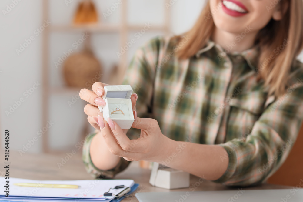 Female wedding planner with ring working at table in office, closeup