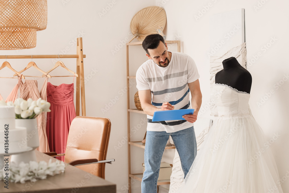 Male wedding planner working with dress in office