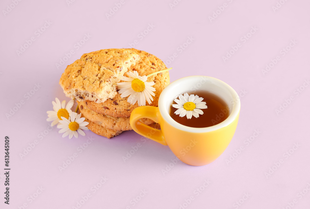 Cup of natural chamomile tea with cookies and flowers on pink background