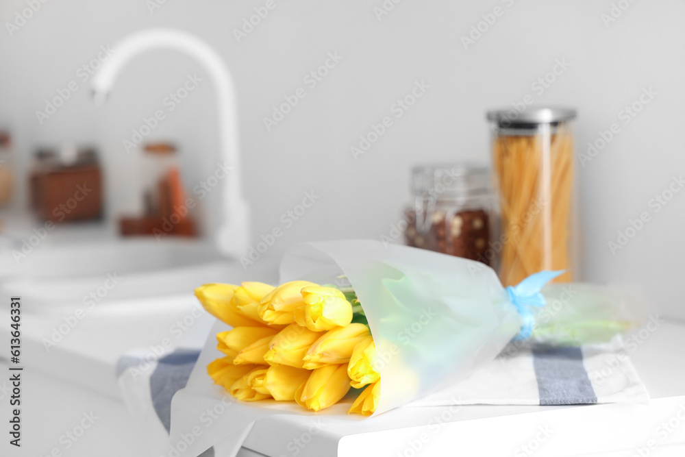 Bouquet of yellow tulip flowers on countertop near kitchen sink, closeup