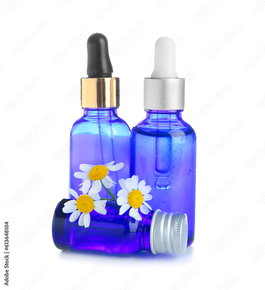 Bottles of healthy essential oil and chamomile flowers on white background