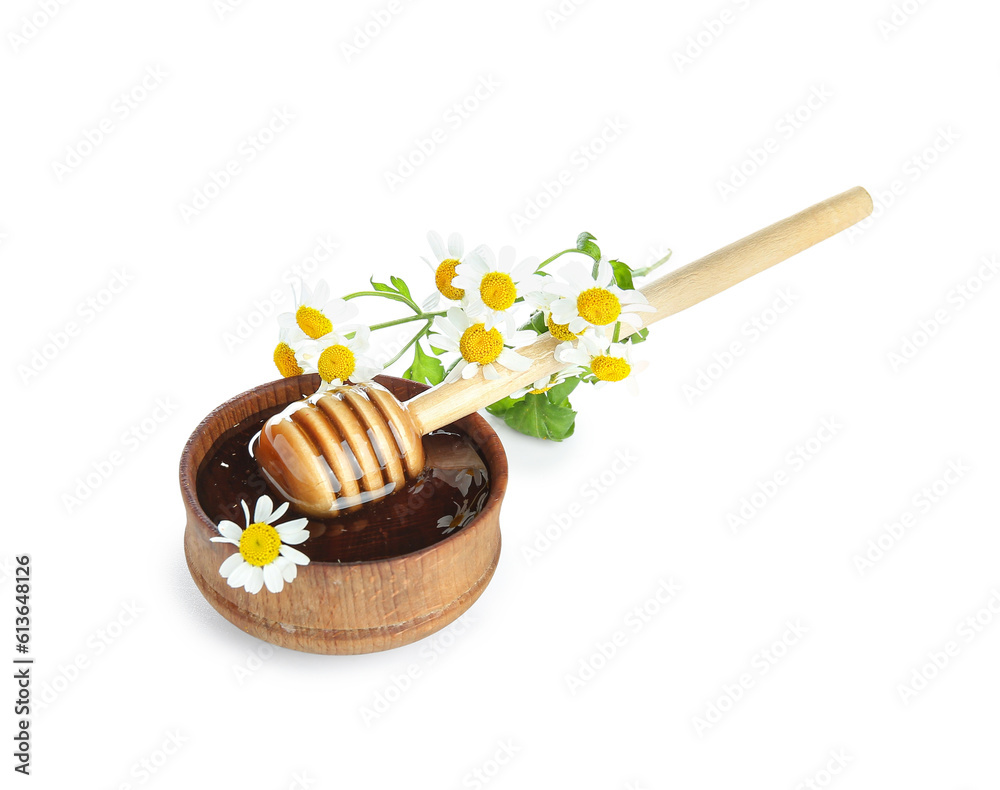 Wooden bowl of honey with dipper and chamomile flowers on white background