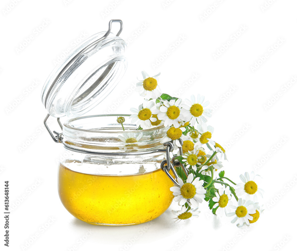 Glass jar of honey and fresh chamomile flowers on white background