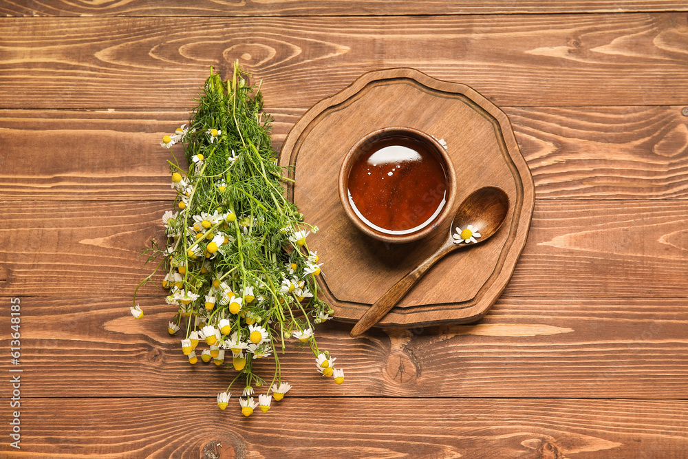 Board with bowl of honey and fresh chamomile flowers on wooden background