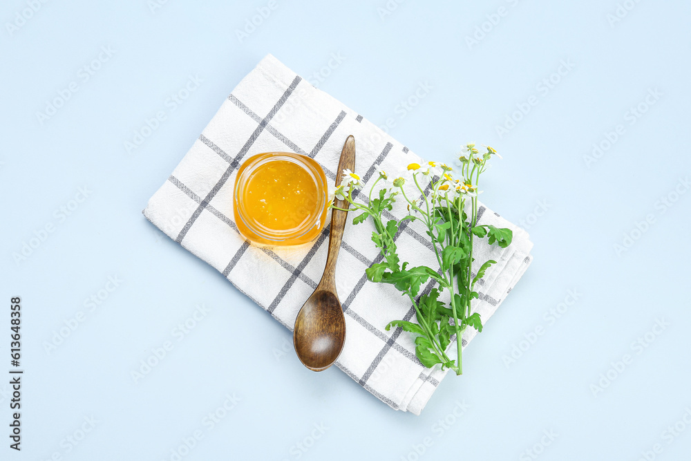 Composition with jar of honey, chamomile flowers and napkin on light background