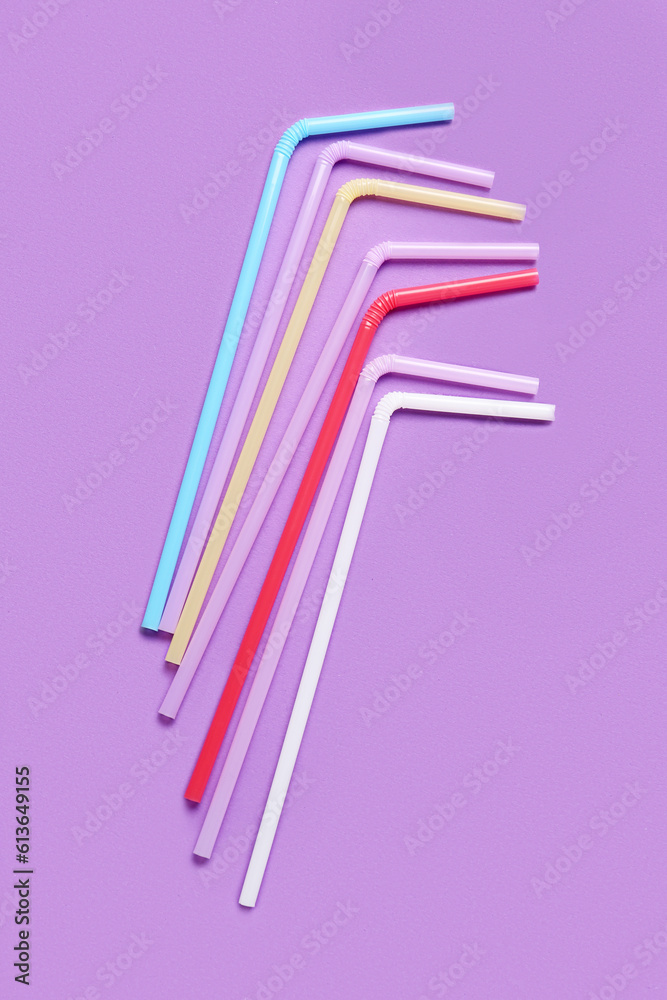 Different plastic straws on purple background