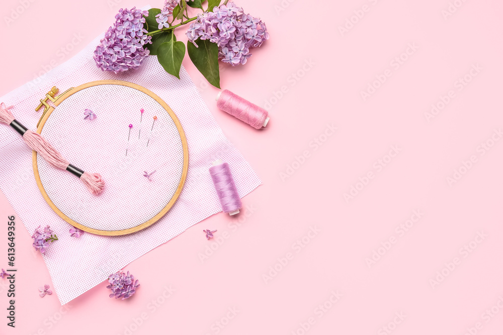 Wooden embroidery hoop with canvas, mouline threads and ball pins on pink background