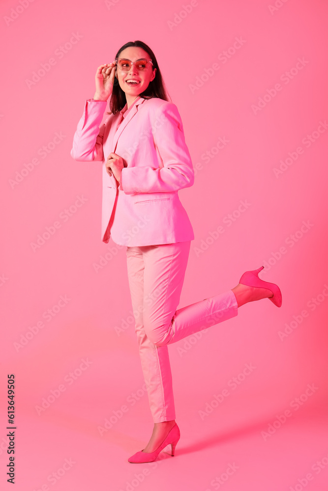 Young woman in stylish suit on pink background