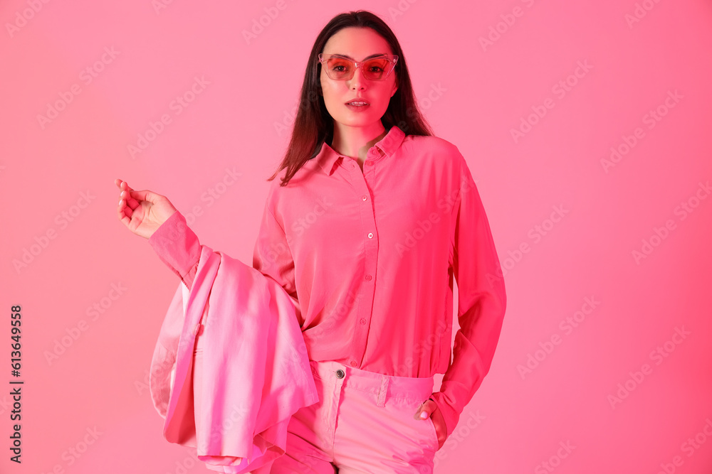 Young woman in stylish suit on pink background