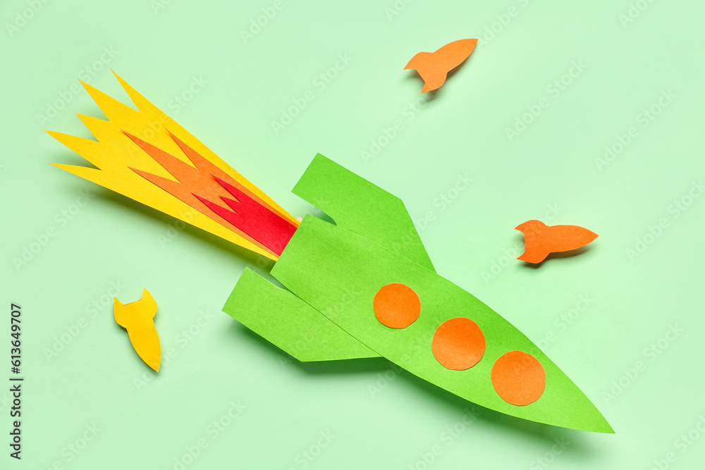 Colorful paper rockets on pale green background