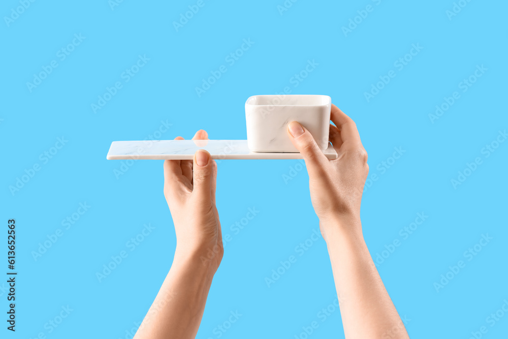 Female hands holding dish and bowl on blue background