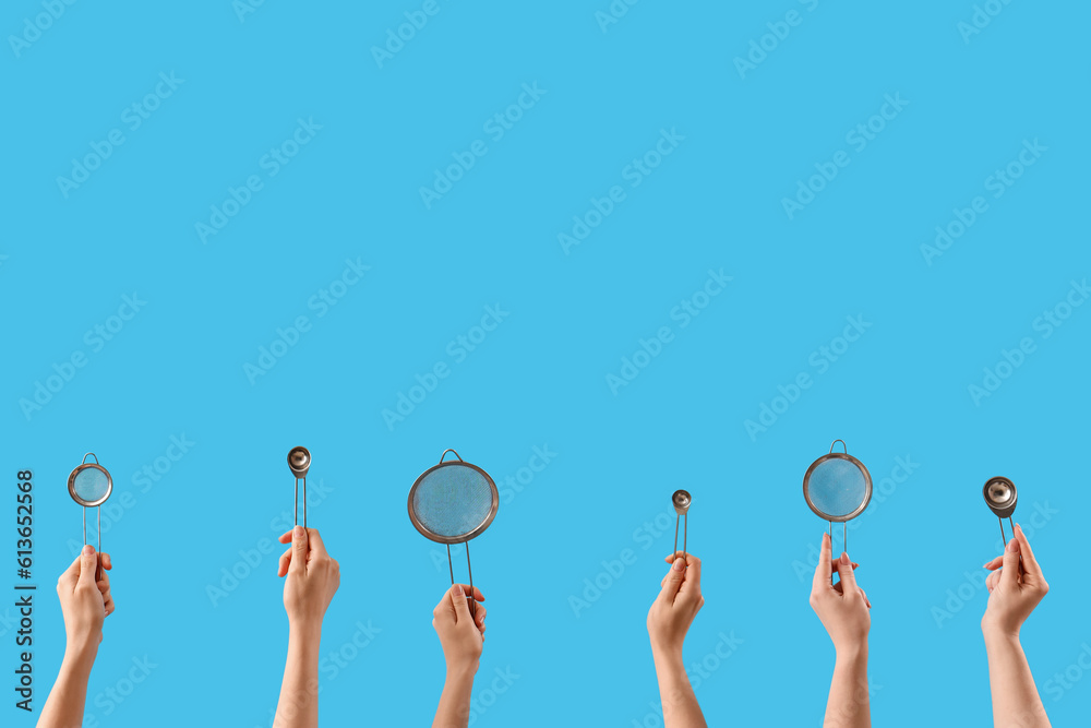 Female hands holding sieves and tea infusers on blue background