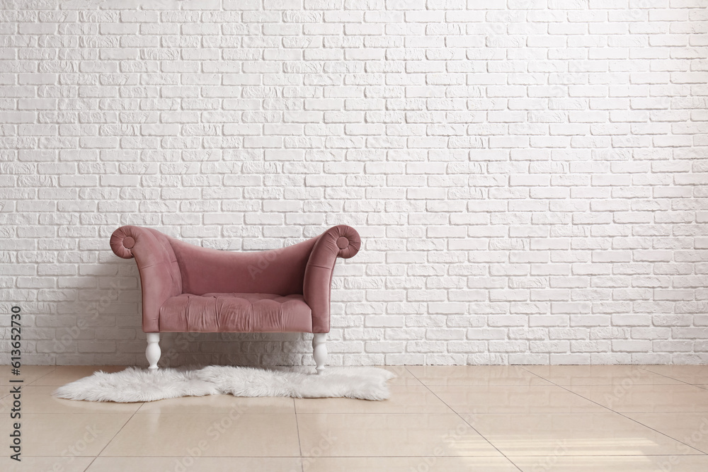 Cozy pink armchair and fur rug near white brick wall