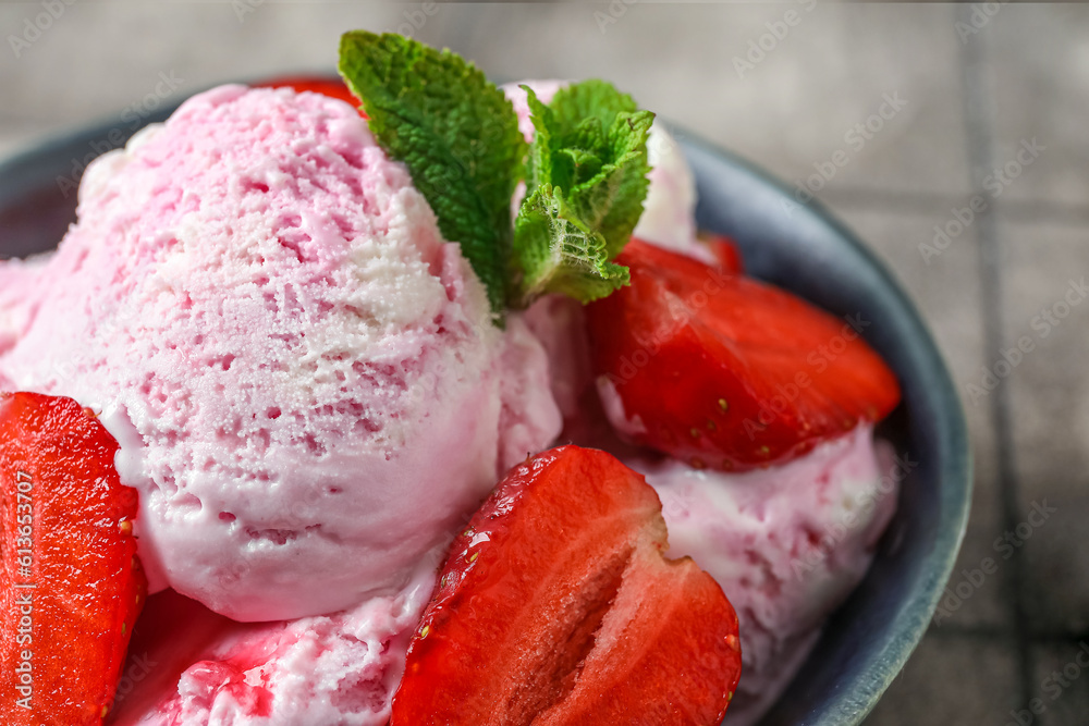 Bowl of strawberry ice cream with berries and mint on grey tile table