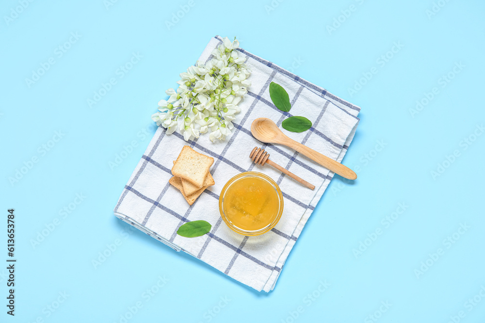 Composition with sweet honey, acacia flowers and crackers on blue background