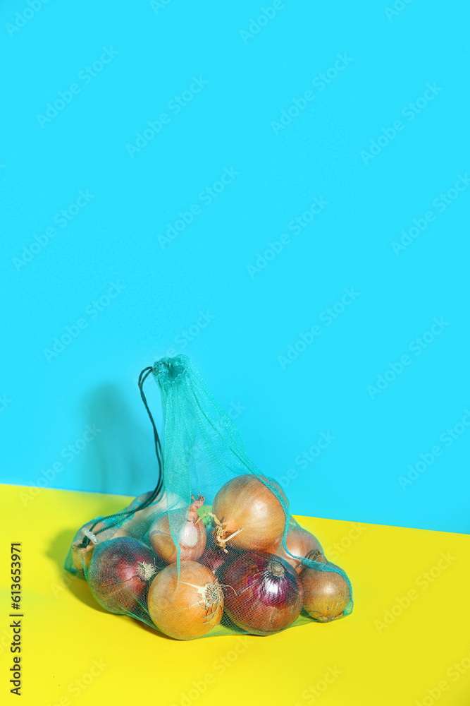 Eco bag with different kinds of onion on color background