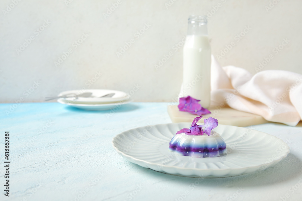 Plates of panna cotta with beautiful hydrangea flowers on blue table