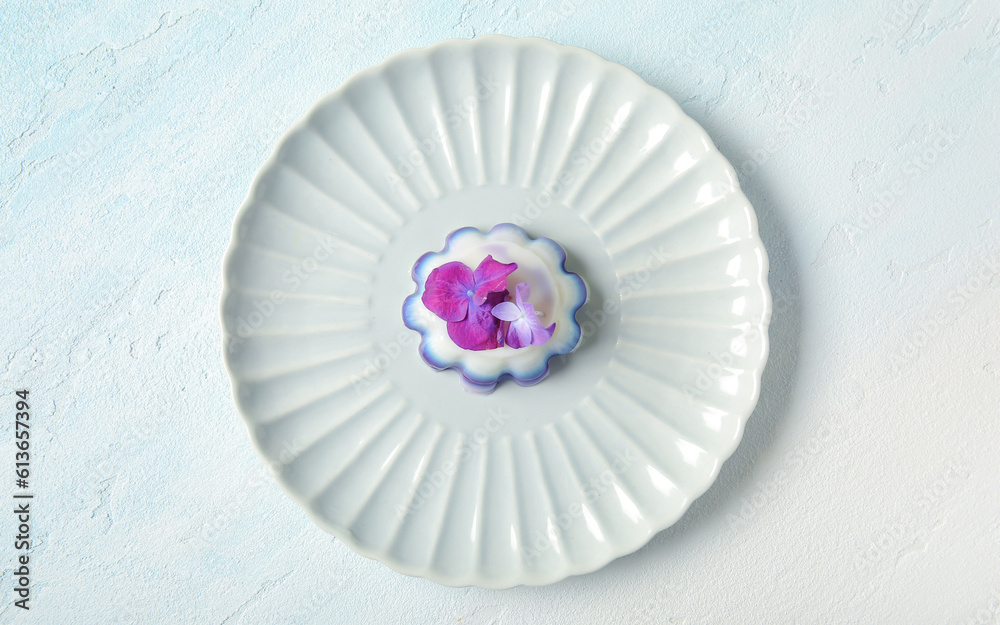 Plate of panna cotta with beautiful hydrangea flowers on white table