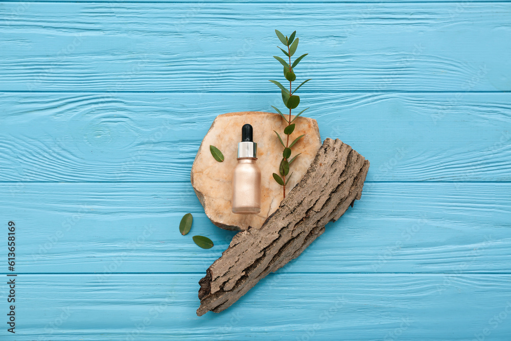 Composition with bottle of cosmetic product, stone, tree bark and eucalyptus branch on color wooden 