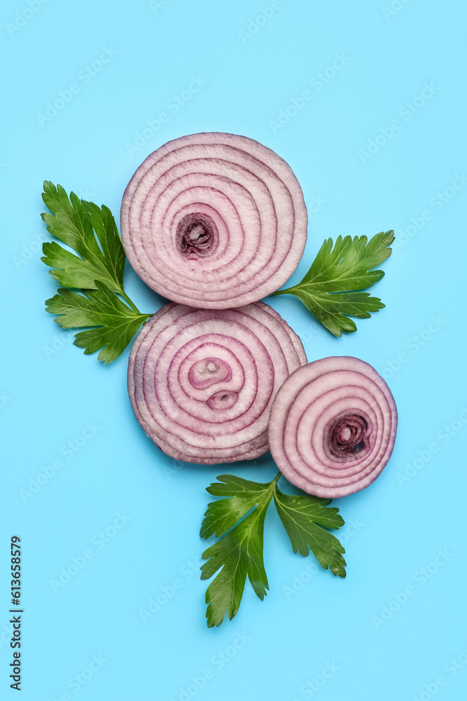 Fresh onion slices and parsley leaves on blue background