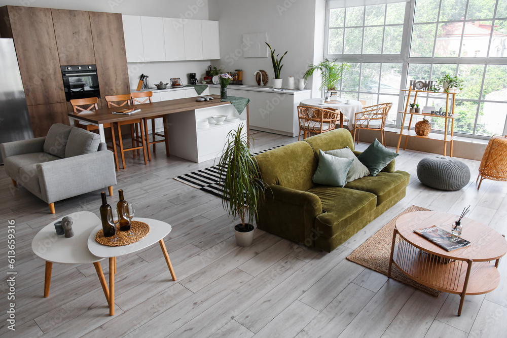 Interior of light open plan kitchen with green sofa and coffee table