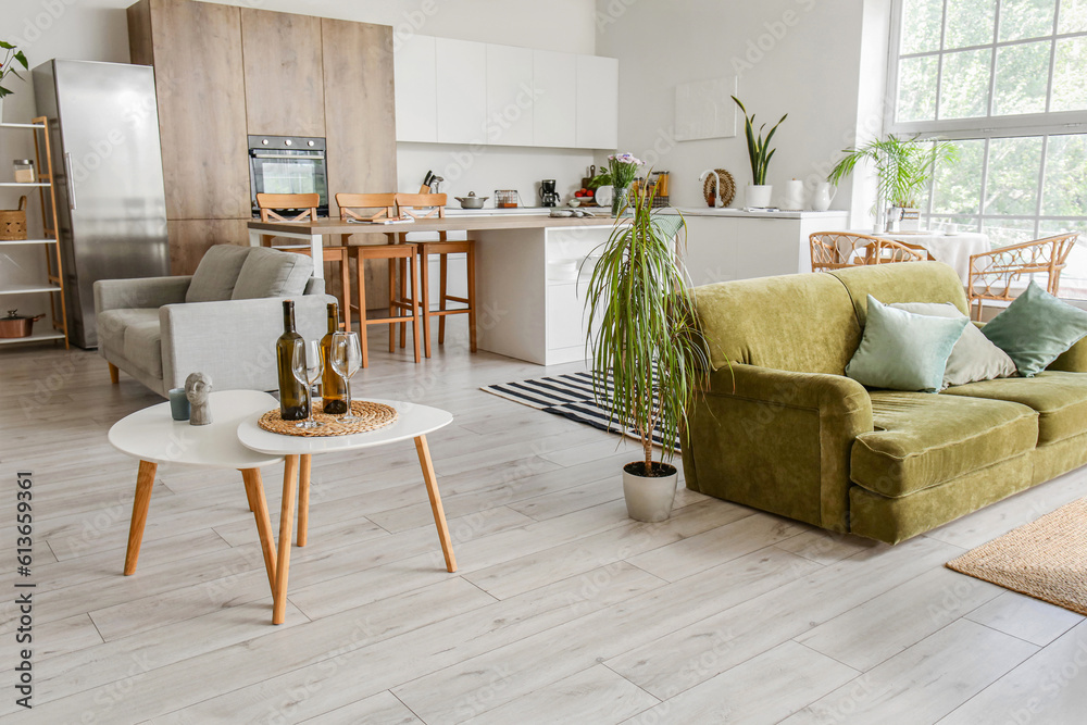 Interior of light open plan kitchen with green sofa and coffee table