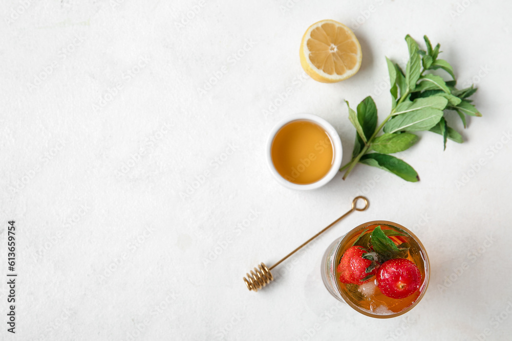 Glass of ice tea with strawberry and mint on white background