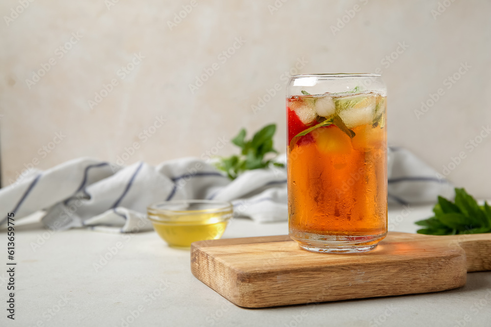 Glass of ice tea with strawberry and mint on white background