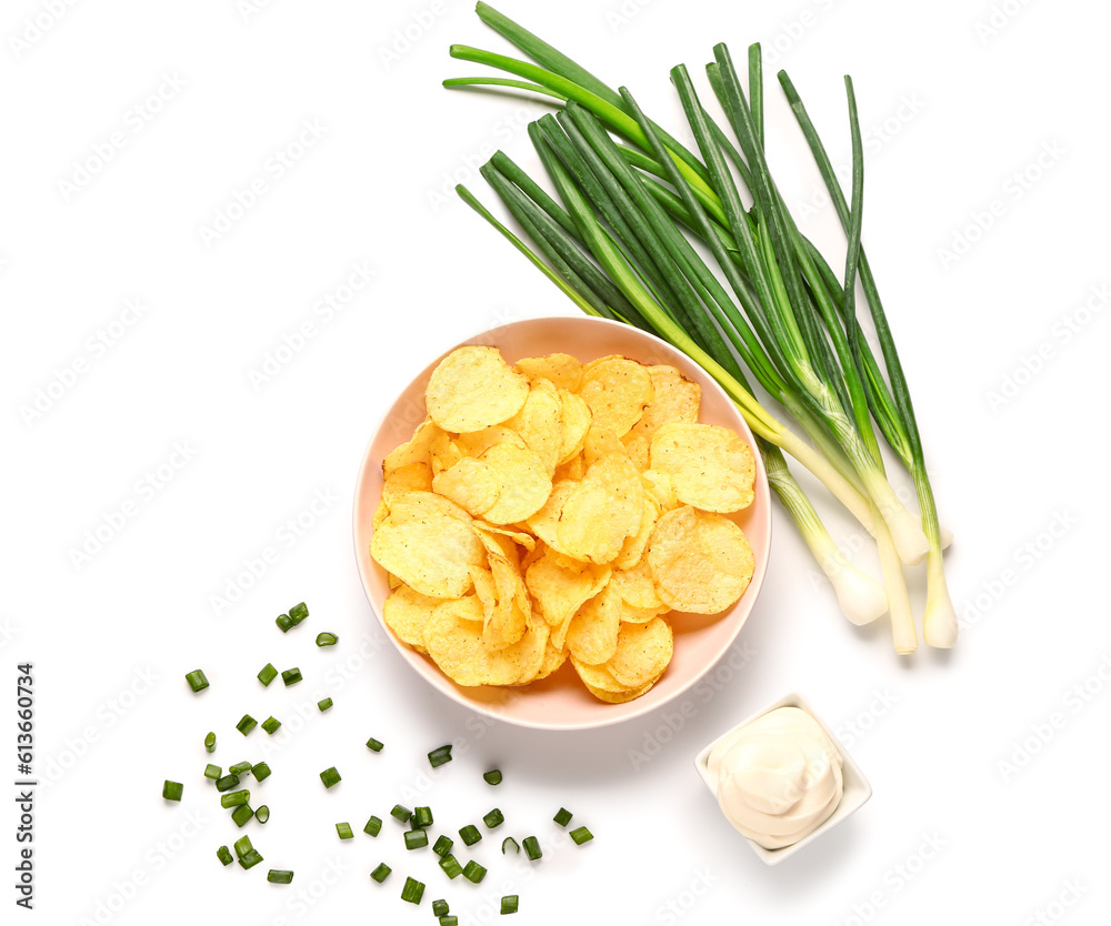 Bowl of tasty sour cream with sliced green onion and potato chips on white background