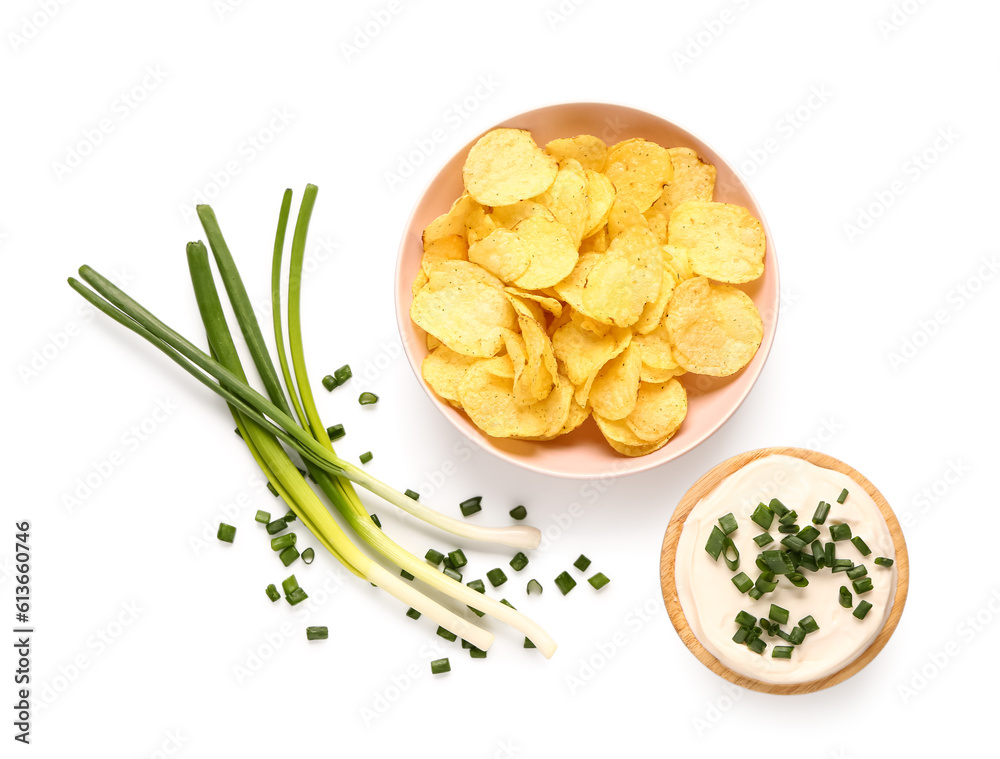 Bowl of tasty sour cream with sliced green onion and potato chips on white background