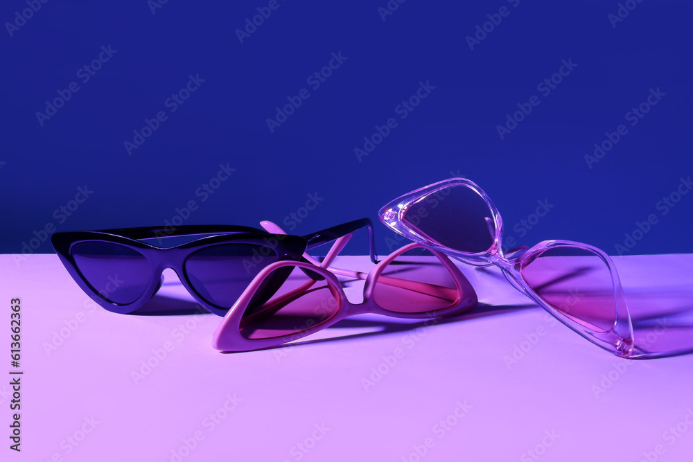 Different stylish sunglasses on colorful background