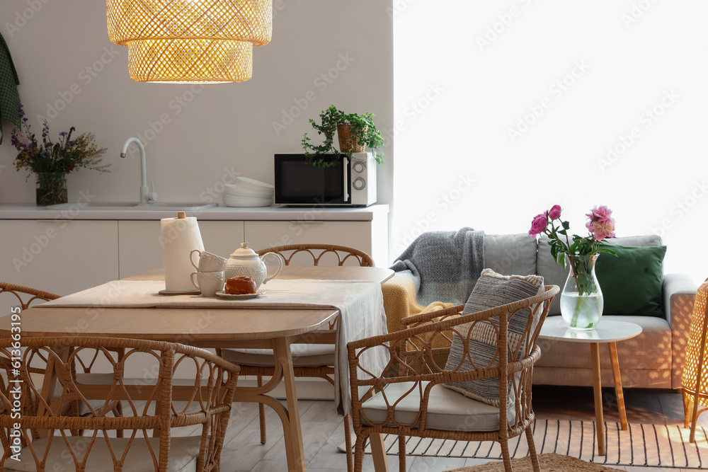 Interior of modern kitchen with glowing lamp and teapot on dining table