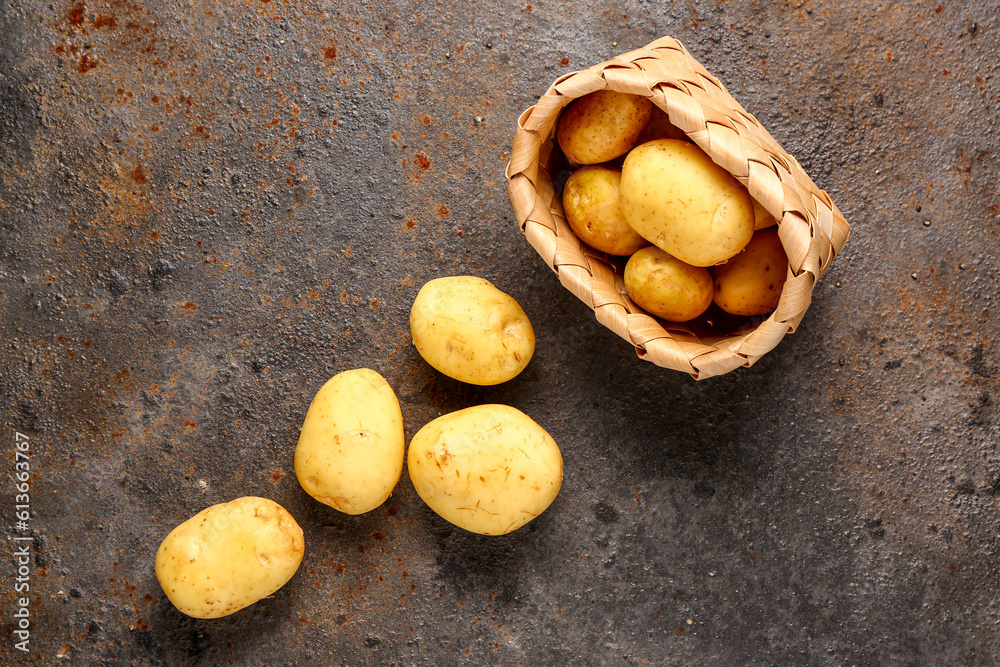 Wicker basket with raw baby potatoes on dark background