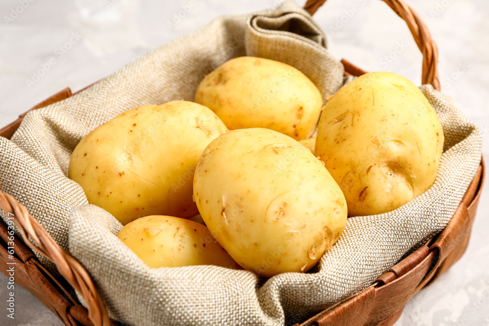 Wicker basket with raw baby potatoes on grey background